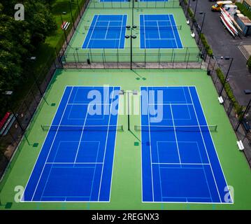 Mit Blick auf sechs Tennisplätze, die für Pickleball gesäumt sind, mit blauer und grüner Oberfläche und Lichtern zum Spielen in der Nacht. Stockfoto
