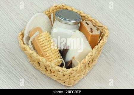 Naturkosmetika. Handgefertigte Kosmetikprodukte. Kosmetikprodukte für Körper und Zubehör in einem weißen Strohkorb auf Holzhintergrund. Stockfoto