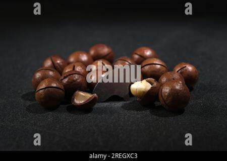 Macadamianüsse mit einem Schlüssel auf schwarzem Hintergrund. Stockfoto