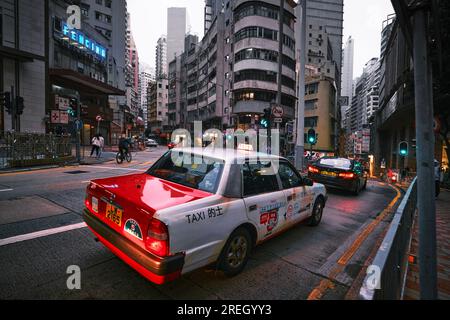 Hongkong, China - 24. April 2023: Rotes Taxi am Abend in der Hong Kong Street Stockfoto