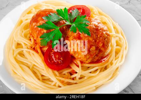 Spaghetti serviert mit Fleischbällchen in Tomatensoße auf weißem Teller, Nahaufnahme Stockfoto