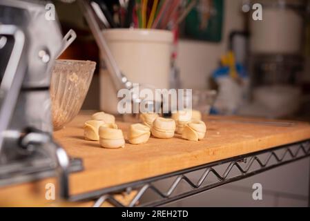 Pasta und Tortellini zuhause auf Holzständer und Chrome Pasta Maker Stockfoto