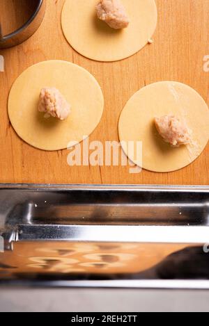 Pasta und Tortellini zuhause auf Holzständer und Chrome Pasta Maker Stockfoto