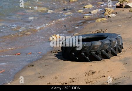 Wasserverschmutzung - weggeworfener Reifen an einem Strand in Portugal Stockfoto