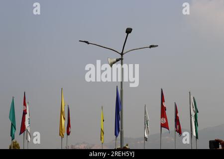 Vierarmiges Straßenlicht auf blauem Himmelshintergrund mit bunten Flaggen daneben Stockfoto