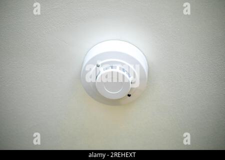 Fire alarm detector on the ceiling with white background. Close-up. Stock Photo