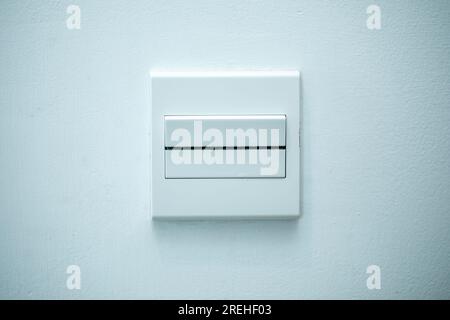 Long flat white on-off switch attached to white wall. White background. Close-up. Stock Photo