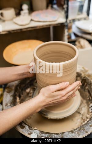 Schnittbild der Hände einer Kunsthandwerkerin, die Tonvase auf einem Töpferrad in der Werkstatt herstellt Stockfoto