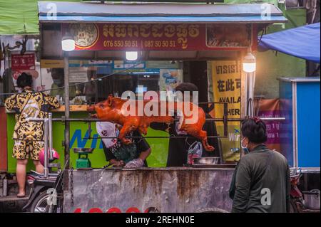 Ein Kambodschaner, der eine Gesichtsmaske trägt, wartet während der COVID-19-Pandemie auf Schweinebraten. Kandal Market, Phnom Penh, Kambodscha. © Kraig Stockfoto