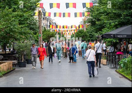 Stadtzentrum von Brüssel, Belgien, 20. Juli 2023 - Menschen jeden Alters laufen auf der Fußgängerzone Anspach Avenue mit Flaggen für den Nationalfeiertag Stockfoto