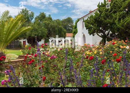 Oceanside, Kalifornien, 2016. Der farbenfrohe Garten der Mission San Luis Rey (18. Jahrhundert) im Sommer mit dem berühmten Pfefferbaum im Hintergrund Stockfoto