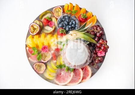 Servierplatte mit rohem Obst und Beeren auf dem Teller, auf dem weißen Tisch Stockfoto