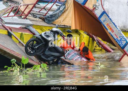 Binangonan, Philippinen. 28. Juli 2023. Ein Einwohner in der Nähe beobachtet das gekenterte motorisierte Boot Princess Aya am Laguna Lake. Ein motorisiertes Boot namens Prinzessin Aya wurde mitten am 27. Juli 2023 aufgrund des starken Windes des Taifuns Doksuri und des Südwestmonsoon in Binangonan gekentert. Das Passagierboot beförderte schätzungsweise 70 Passagiere, von denen 40 überlebten und 26 Passagiere für tot erklärt wurden. Laut den Ermittlungen und der philippinischen Küstenwache, kann das motorisierte Boot nur maximal 42 Passagiere aufnehmen, der Kapitän und Besatzungsmitglieder. Der Abrufvorgang für Stockfoto