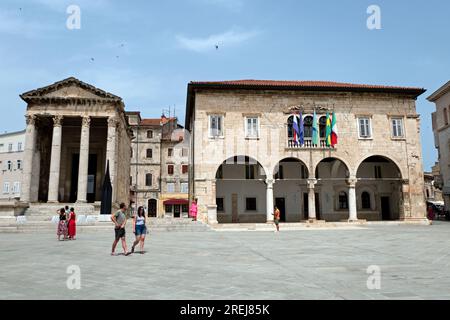 Blick auf Pula (Pola) in Kroatien mit Menschen und Sehenswürdigkeiten: Tempel des Augustus und Rathaus. Touristen, die im Sommer in kroatischer Stadt spazieren gehen, besuchen Stockfoto