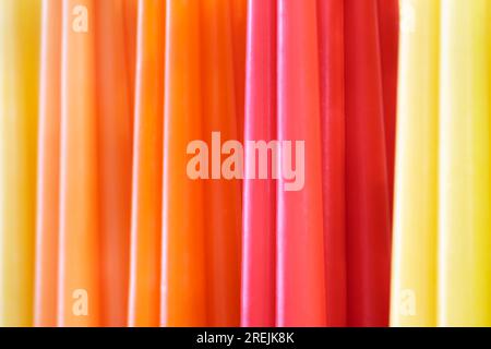 Große Gruppe von bunten Wachskerzen, abstrakte parallele Linien, lebendige, warme Farben auf dem Hintergrund Stockfoto