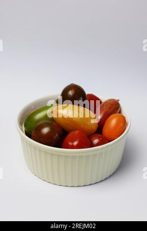 Eine Schüssel mehrfarbige Tomaten der Saison auf weißem Hintergrund Stockfoto