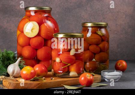 Verschiedene Tomatenkonserven mit Äpfeln, Meerrettich, Knoblauch und Chili-Pfeffer in Glasgefäßen zur Langzeitlagerung Stockfoto