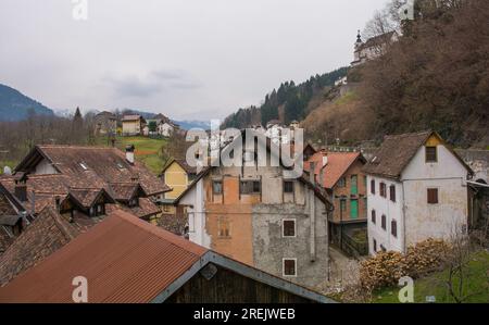 Alte Gebäude im Bergdorf Rigolato in Carnia, Friaul-Julisch Venetien, Norditalien. Heilige Philip und James Parish Kirche oben rechts Stockfoto