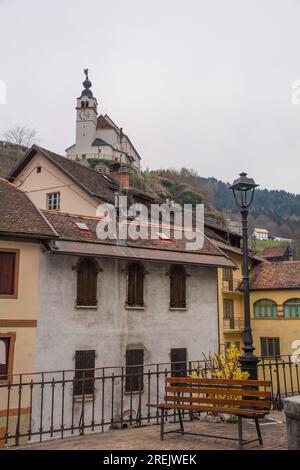 Alte Gebäude im Bergdorf Rigolato in Carnia, Friaul-Julisch Venetien, Norditalien. Heilige Philip und James Parish Church im Hintergrund Stockfoto