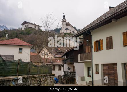 Alte Gebäude im Bergdorf Rigolato in Carnia, Friaul-Julisch Venetien, Norditalien. Heilige Philip und James Parish Church im Hintergrund Stockfoto