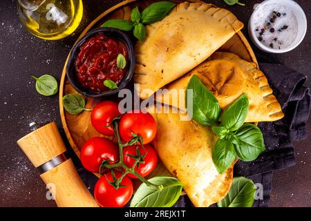 Hausgemachte Pasteten, gebackenes Gebäck mit Fleisch oder Gemüse. Italienische Calzone geschlossene Pizza, mexikanische Empanada, Karaim ukrainische Pasteten. Mit hausgemachtem Toma Stockfoto