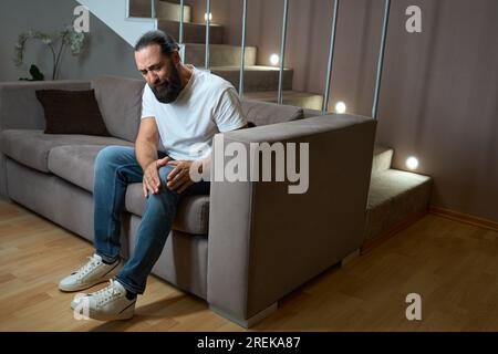 Männlich in lässiger Kleidung leidet an Knieschmerzen Stockfoto