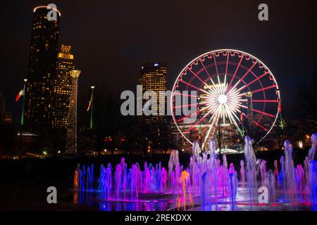 Farbenfrohe Springbrunnen ergänzen das SkyView Riesenrad im Centennial Olympic Park in Atlanta bei Nacht. Stockfoto