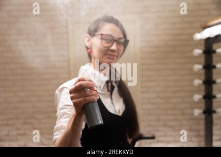 Die Friseurin benutzt ein Spray bei ihrer Arbeit Stockfoto