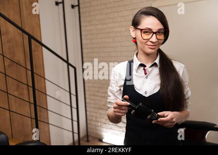 Friseurfrau reinigt Haarschneider mit Spezialbürste Stockfoto