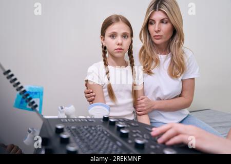 Trauriges Mädchen mit ihrer Mutter beim Arzttermin in der Klinik Stockfoto