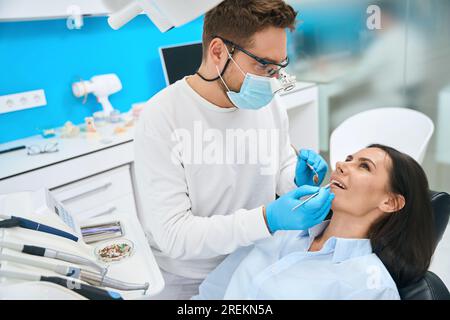 Fachzahnarzt mit Mundspiegel und Sichelsonde zur Überprüfung der Zahngesundheit Stockfoto