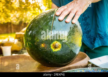 Nahaufnahme eines Mannes, der eine Wassermelone schneidet Stockfoto