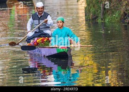 Rainawari, Srinagar, Jammu und Kaschmir, Indien. 25. Oktober 2022. Vater und Sohn bringen Blumen auf den Markt in einem traditionellen Shikara-Boot am Dal Lake Stockfoto