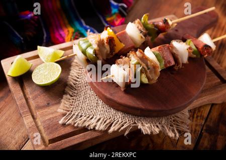 Hausgemachte Spieße mit Fleisch und gegrilltem Gemüse, serviert auf einem rustikalen Holzbrett, auch bekannt als Brochetten, alambre, Chuzo oder Pincho. Stockfoto