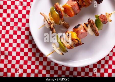 Hausgemachte Spieße mit Fleisch und gegrilltem Gemüse, serviert auf einem rustikalen Holzbrett, auch bekannt als Brochetten, alambre, Chuzo oder Pincho. Tabelle topview. Stockfoto