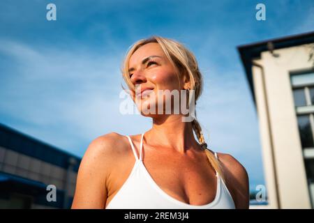 Porträt einer mittelalterlichen, wunderschönen blonden Frau im Sonnenuntergang draußen. Weibliche Sportlerin mit Kopfschuss im Freien. Stockfoto