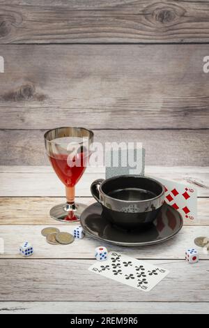 Ein wunderschönes Stillleben mit einer Tasse Kaffee, einem Glas Alkohol und Glücksspiel auf einem weißen Holztisch Stockfoto