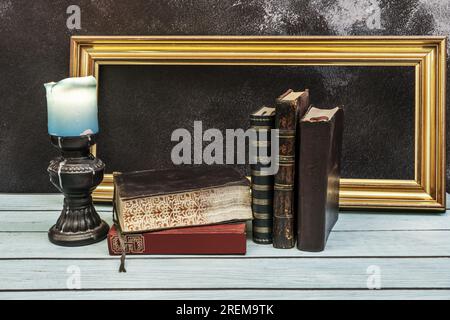 Ein Stillleben mit alten Büchern, einer Kerze und einem goldenen Rahmen Stockfoto