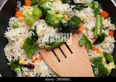 Leckerer gebratener Reis mit Gemüse und Holzspachtel in der Pfanne, Draufsicht Stockfoto