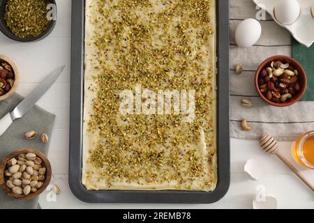 Ich mache köstliche Baklava. Backpfanne mit Teig und Zutaten auf weißem Holztisch, flach liegend Stockfoto