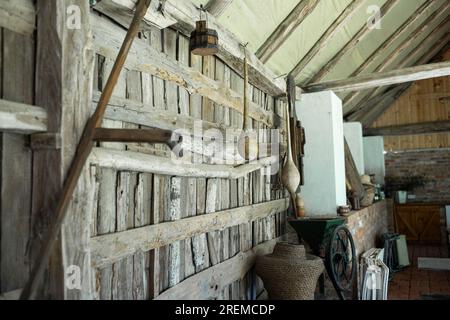 An der Wand in der Scheune hing eine antike Sense. Alte landwirtschaftliche Werkzeuge. Hochwertiges Foto Stockfoto