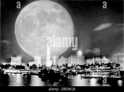 Miami, Florida: 18. Juni 1965 der Vollmond über Miami wurde vom Fotografen übertrieben, indem er den Film für eine doppelte Belichtung durchdacht hatte, als er Downtown Miami mit einem Weitwinkelobjektiv drehte. Stockfoto