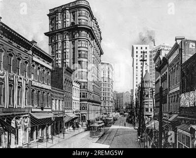 Atlanta, Georgia: ca. 1905 Eine Fotogravur, in der Trolley-Autos auf der Lower Peachtree Street zusammen mit Lester's Book Store, dem Flatiron Building und dem Piedmont Hotel gezeigt werden, Stockfoto