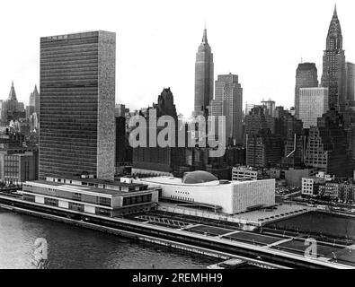 New York, New York: November 1953 Mid-town Manhattan, einschließlich des United Nations Building auf der linken und vorderen Seite, wird in voller Pracht gezeigt mit diesem Foto, das aus einem Flugzeug gemacht wurde, das entlang des East River fliegt. Das Chrysler Building ist das hohe Gebäude auf der rechten Seite, während sich das Empire State Building in der Mitte befindet. Stockfoto