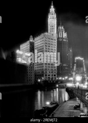 Chicago, Illinois: ca. 1936. Das Wrigley Building auf der linken Seite mit dem Tribune Tower auf der rechten Seite, wie bei Nacht auf der anderen Seite des Flusses in der Skyline von Chicago zu sehen. Stockfoto