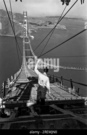 San Francisco, Kalifornien: Dezember 1935. Ein Bauarbeiter steht an einem Ende der Laufstege, die sich über das Golden Gate zwischen den beiden Türmen erstrecken. Stockfoto