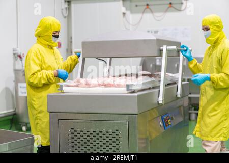 Das Verfahren der Verpackung von rohem Hühnerfleisch in einem Vakuumbeutel und der Versiegelung mit einem Vakuumgerät. Stockfoto