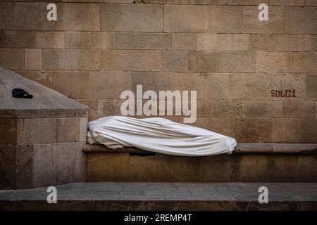 Barcelona, Spanien. 28. Juli 2023. Ein Obdachloser schläft früh am Morgen in einem weißen Sack rund um die Kathedrale von Barcelona. Kredit: SOPA Images Limited/Alamy Live News Stockfoto