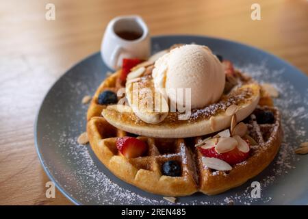 Waffel mit Eis und Heidelbeere, Erdbeere, Banane und Honig, serviert auf einem Teller Stockfoto