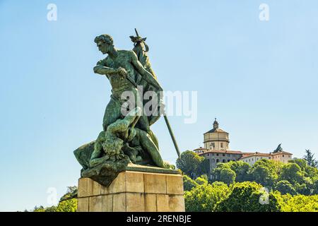 Ponte Umberto 1 in Turin, eine der vier Statuen, die Tapferkeit repräsentieren. Im Hintergrund die Kirche Santa Maria del Monte dei Cappuccini. Piemont, Stockfoto